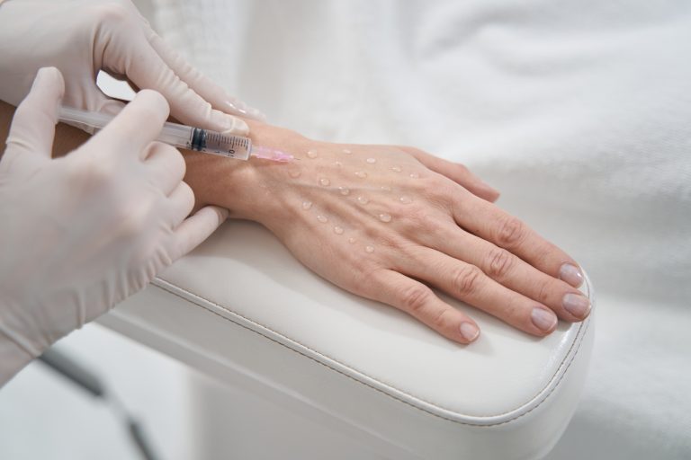 Woman receiving hand rejuvenation injection in beauty salon